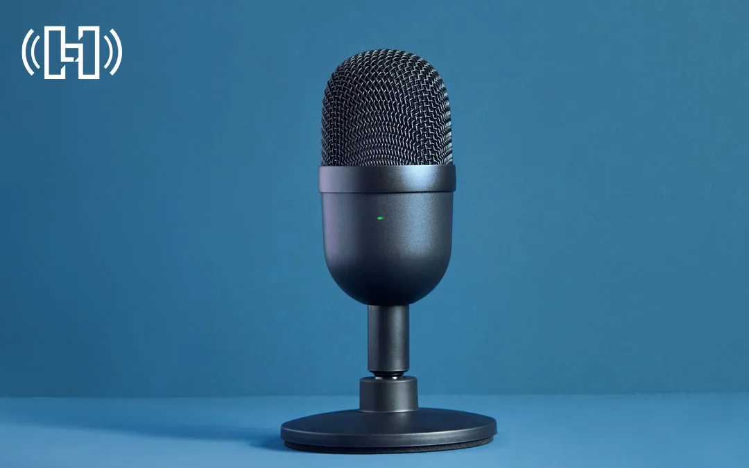 Black podcast microphone with blue desk and background